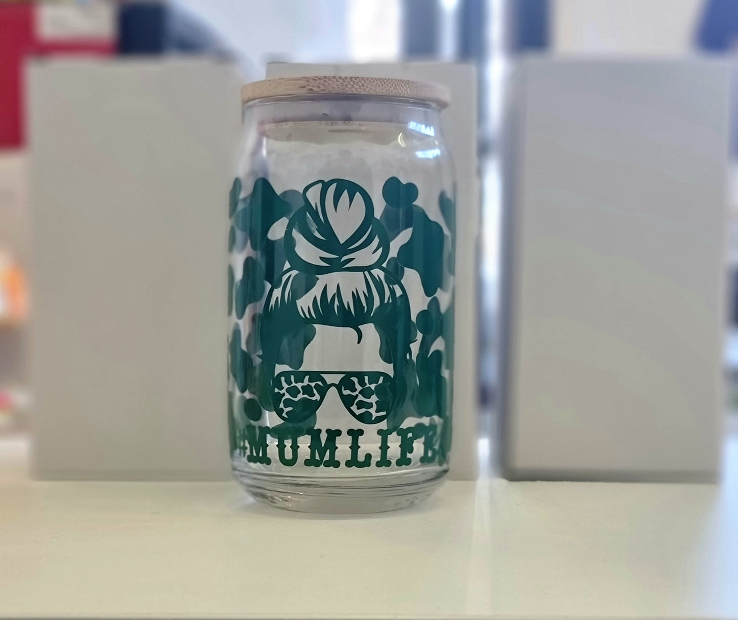 A 16oz glass tumbler with a graphic design and a reusable straw, the graphic includes a hairstyle and the text '#Mumlife'.