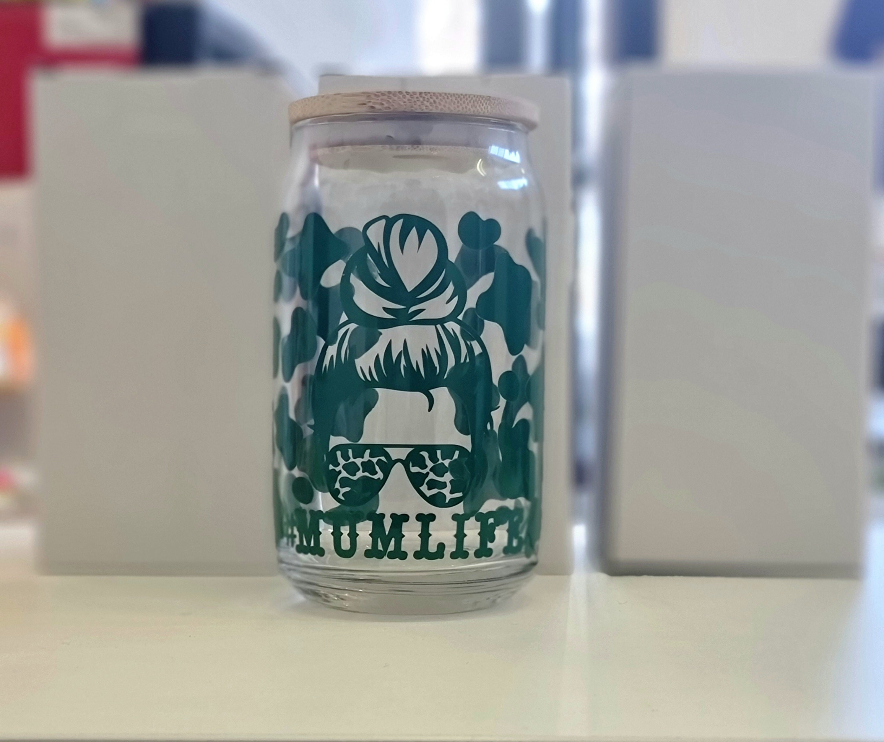 A 16oz glass tumbler with a graphic design and a reusable straw, the graphic includes a hairstyle and the text '#Mumlife'.