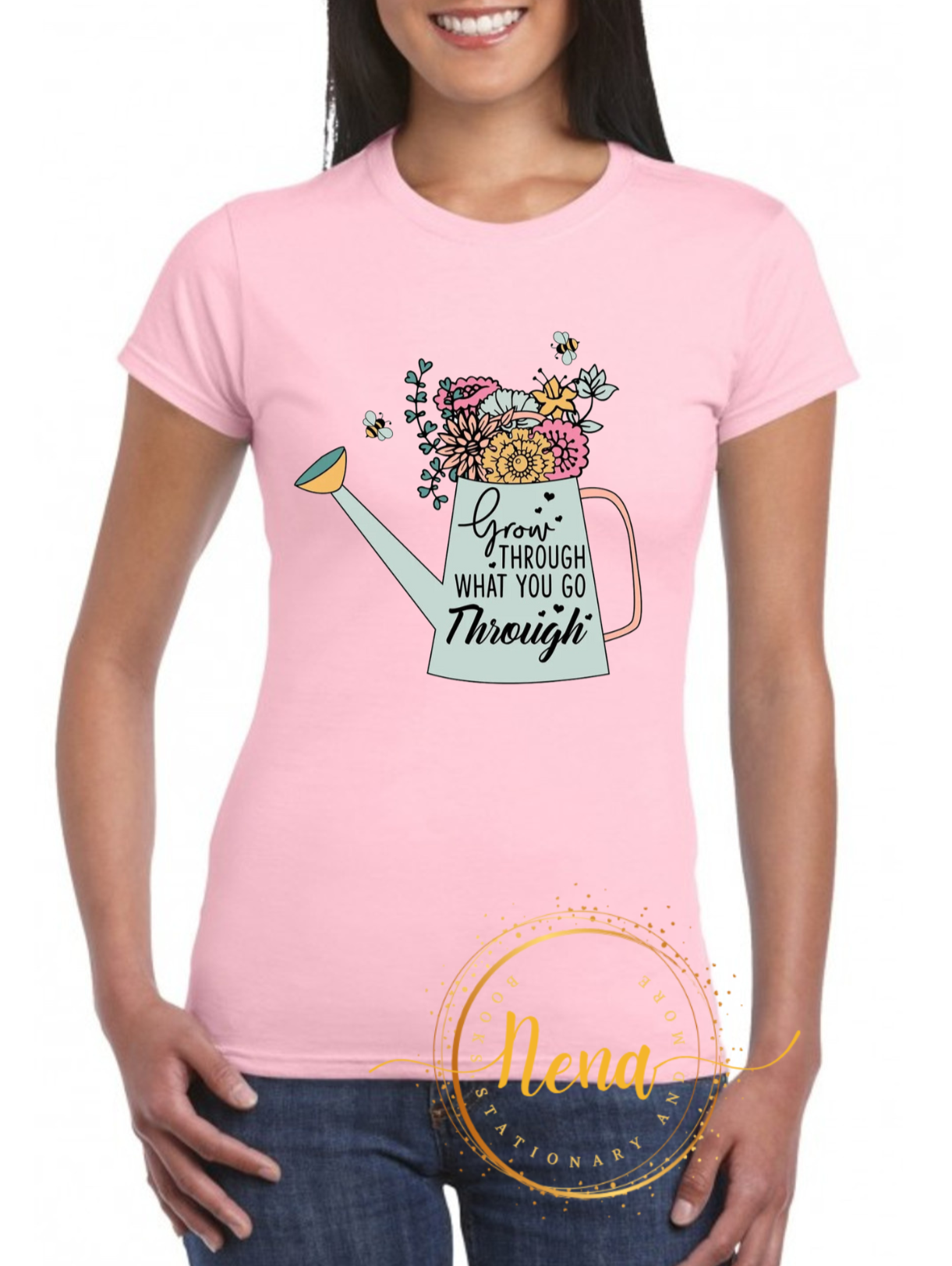 A pink ladies' soft-style t-shirt with a graphic print of a watering can and flowers on the front.