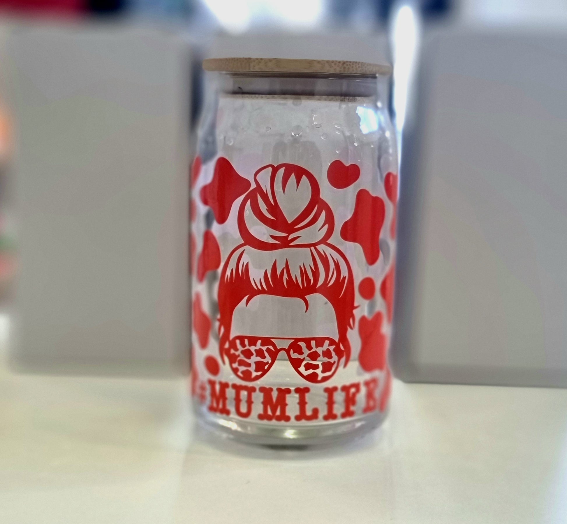 A 16oz glass tumbler with a graphic design and a reusable straw, the graphic includes a hairstyle and the text '#Mumlife'.