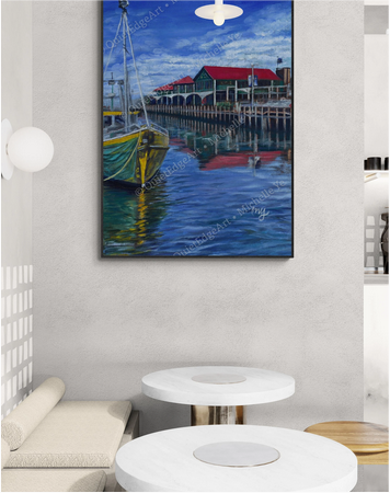 Painting of a harbor scene with boats on a wall in a room with white walls and furniture.