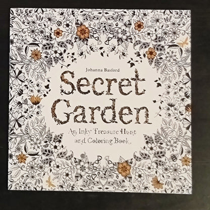 Coloring book titled 'Secret Garden' by Johanna Basford with floral designs on a dark background.